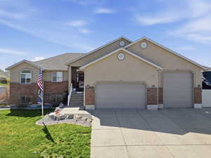 Single story home featuring a garage, brick siding, stucco siding, and driveway