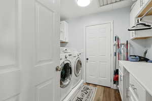 Laundry area featuring cabinet space, dark wood-style flooring, and washing machine and dryer