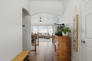 Corridor with dark wood-style flooring, recessed lighting, and arched walkways