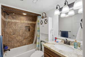 Full bathroom with vanity, shower / tub combo, and a textured ceiling