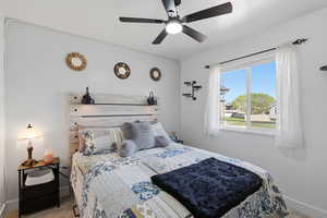 Carpeted bedroom featuring ceiling fan and baseboards