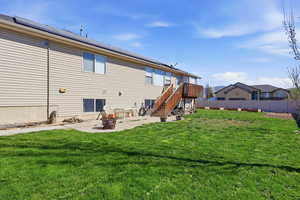 Rear view of house with a fire pit, solar panels, and a patio