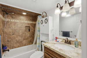 Bathroom with vanity, shower / bath combo, and a textured ceiling