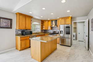 Kitchen featuring light marble finish flooring, light stone counters, stainless steel appliances, tasteful backsplash, and recessed lighting