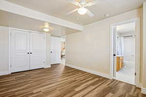 Unfurnished bedroom with light wood-style flooring, a closet, ceiling fan, and ensuite bathroom
