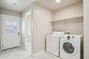 Laundry area featuring light marble finish flooring and separate washer and dryer