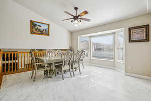 Dining space featuring light marble finish flooring, ceiling fan, and lofted ceiling