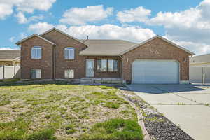 View of front of house with brick siding, a garage, driveway, and roof with shingles