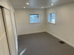 Unfurnished bedroom featuring a closet, dark carpet, multiple windows, and recessed lighting