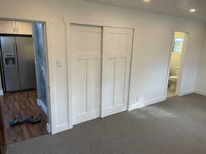 Unfurnished bedroom with stainless steel fridge, a closet, dark colored carpet, recessed lighting, and connected bathroom