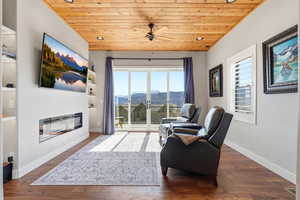 Living area featuring ceiling fan, wooden ceiling, dark wood finished floors, recessed lighting, and a glass covered fireplace