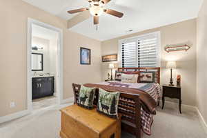 Bedroom featuring light colored carpet, ceiling fan, and connected bathroom