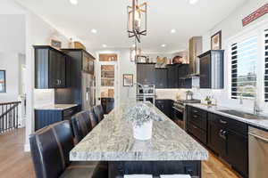 Kitchen with a kitchen bar, tasteful backsplash, light stone countertops, and premium appliances