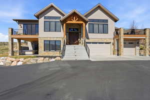 View of front of property with stone siding, driveway, and a garage