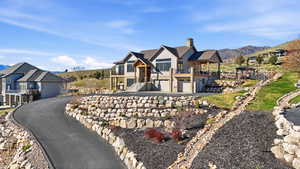 View of front of house with an attached garage, a chimney, a balcony, and a mountain view