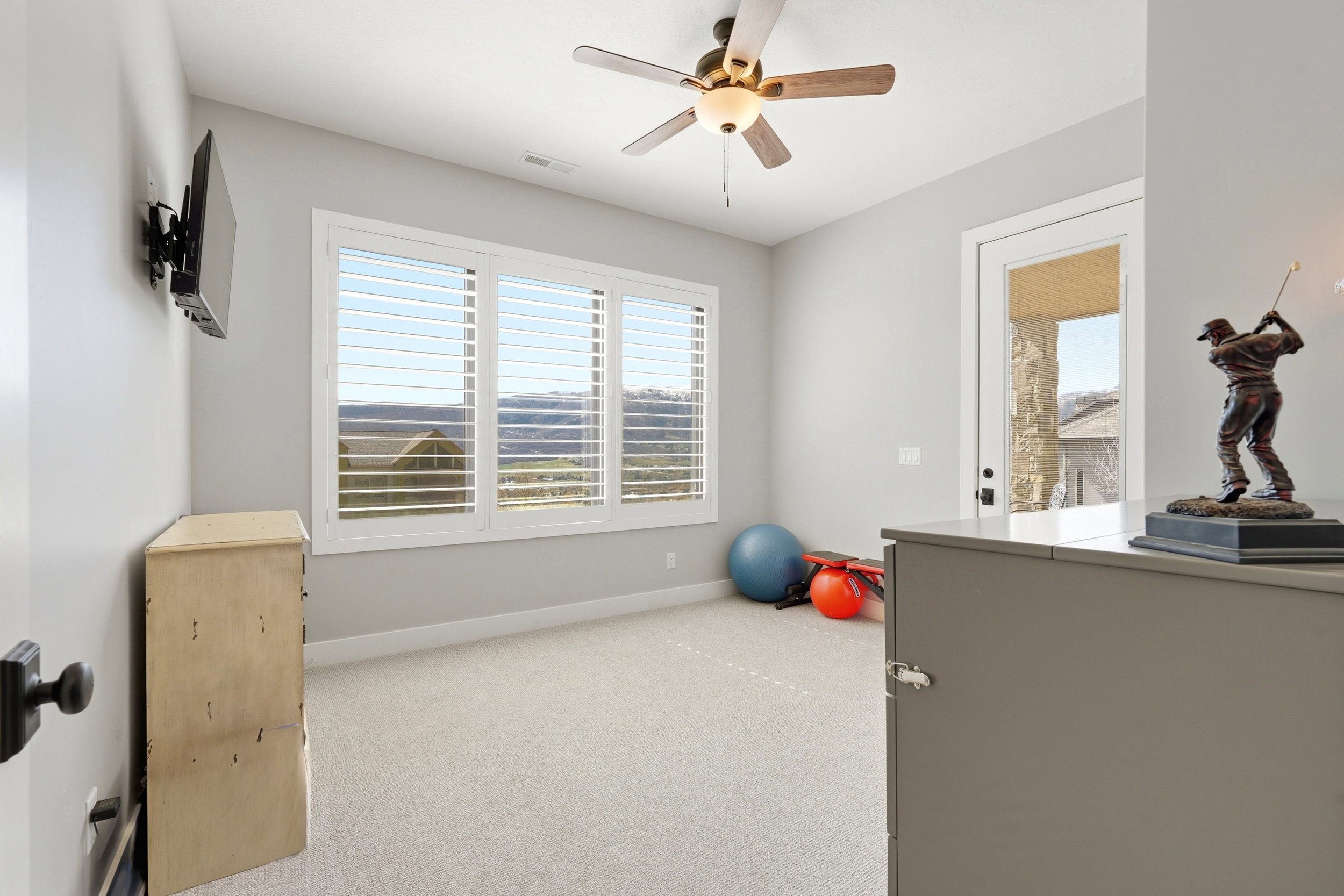 Exercise room featuring a ceiling fan, light carpet, and healthy amount of natural light