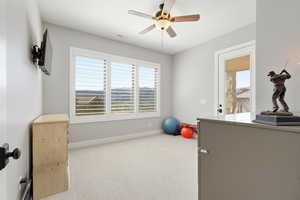 Exercise room featuring a ceiling fan, light carpet, and healthy amount of natural light