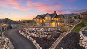 View of front of home featuring a balcony, a chimney, a garage, driveway, and a mountain view