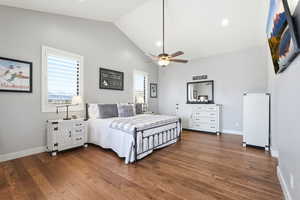 Bedroom with vaulted ceiling, dark wood-style floors, ceiling fan, multiple windows, and recessed lighting