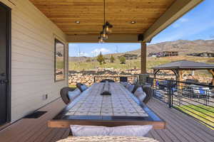 Wooden deck featuring outdoor dining area, a mountain view, and a gazebo