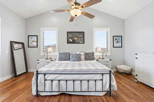 Bedroom with hardwood / wood-style flooring, multiple windows, ceiling fan, and lofted ceiling
