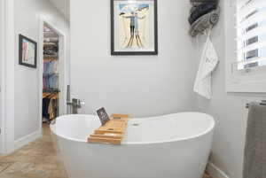 Bathroom with a soaking tub and a walk in closet