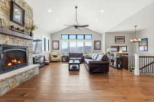 Living area featuring dark wood finished floors, a fireplace, a ceiling fan, a high ceiling, and suspended lighting