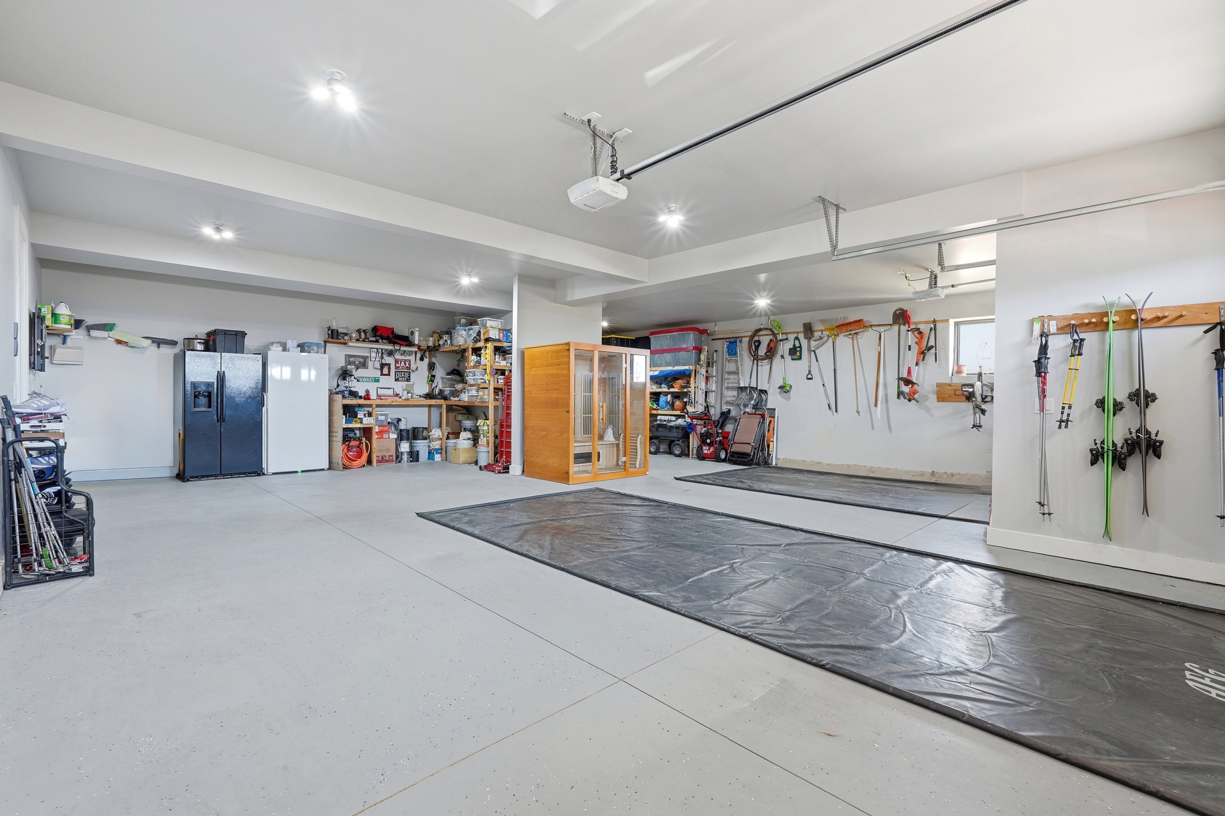 Garage with stainless steel fridge with ice dispenser, freestanding refrigerator, and a garage door opener