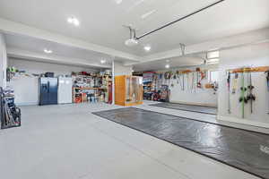 Garage with stainless steel fridge with ice dispenser, freestanding refrigerator, and a garage door opener
