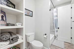 Full bathroom featuring toilet and shower / bathtub combination with curtain