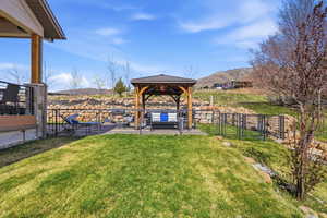 View of green lawn featuring a gazebo, a mountain view, and a patio
