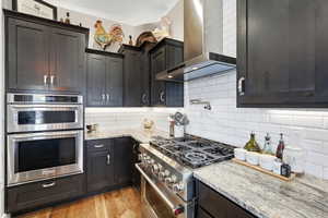 Kitchen featuring stainless steel appliances, light stone counters, tasteful backsplash, and light wood finished floors