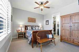 Bedroom featuring light colored carpet, a walk in closet, and a ceiling fan
