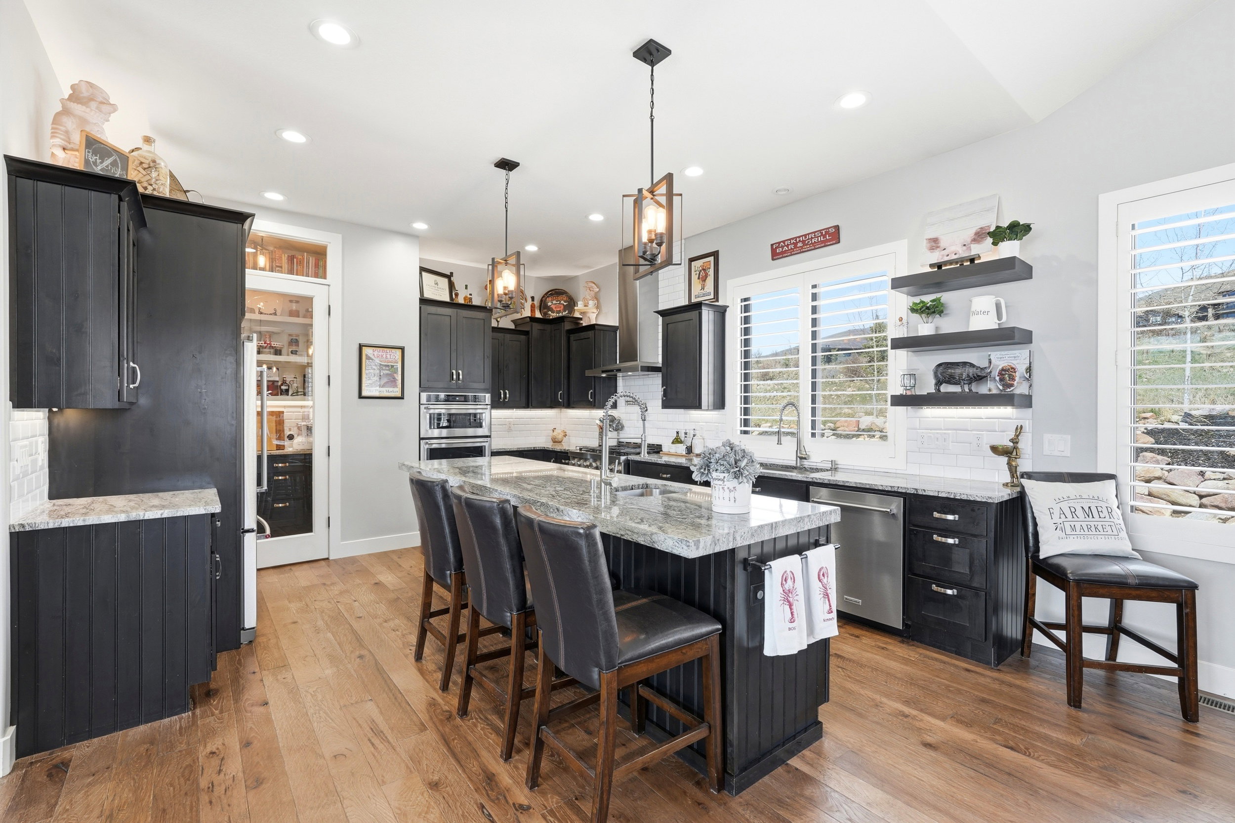 Kitchen with dark cabinetry, a kitchen breakfast bar, light stone counters, decorative backsplash, and an island with sink
