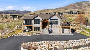 View of front facade featuring stone siding, an attached garage, a mountain view, driveway, and a chimney