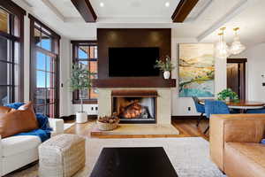 Living room with beam ceiling, light wood-style flooring, a lit fireplace, and recessed lighting