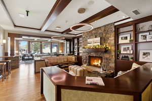 Living area featuring built in features, a fireplace, light wood-type flooring, and beam ceiling