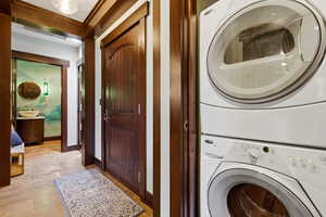 Laundry area with stacked washer and clothes dryer and baseboards