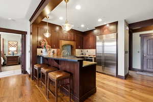 Kitchen featuring stainless steel appliances, hanging light fixtures, a breakfast bar, and light wood-type flooring