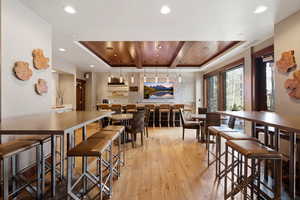 Dining space with a wooden ceiling with exposed beams and light wood-style flooring