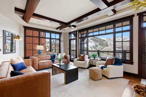 Living area with a mountain view, coffered ceiling, plenty of natural light, and wood finished floors