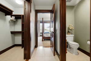 Ensuite bathroom with toilet and light tile patterned floors