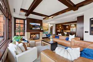 Living area with coffered ceiling, a premium fireplace, and a chandelier