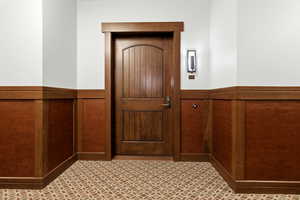 Doorway featuring wainscoting, tile patterned floors, and wooden walls