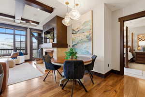 Dining space with wood-type flooring, coffered ceiling, and a fireplace