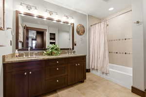 Bathroom with double vanity, shower / bathtub combination with curtain, and recessed lighting