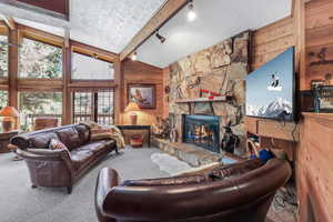 Spacious living room with vaulted ceilings, walls of windows, wood-burning fireplace and open floor-plan