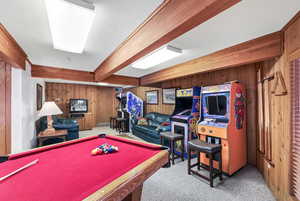 Rec room with billiards table, light colored carpet, beamed ceiling, and wooden walls