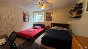 Bedroom with a textured ceiling, light colored carpet, and a ceiling fan