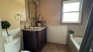 Bathroom with vanity, wainscoting, and light tile patterned flooring